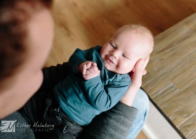 Een glimlach van een pasgeboren baby naar zijn pappa tijdens een newborn lifestyle reportage